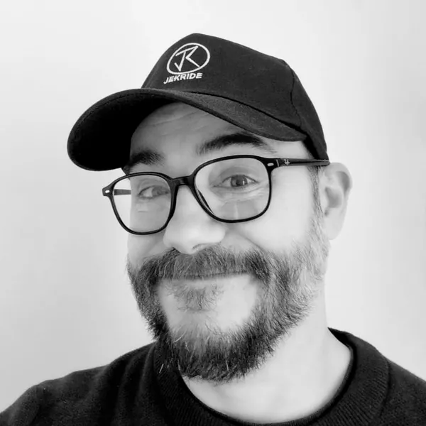 Photo de Jérémy Macedo en noir et blanc allant avec son témoignage. Il a sa casquette qui comporte le logo de son entreprise. Il nous regarde avec un sourir malicieux