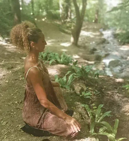 Photo de Rachida Jorf allant avec son témoignage. Elle est en tailleur en train de méditer en pleine nature